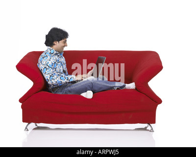 VDA200164 südasiatischen indischer Mann auf Sofa auf Laptop trägt Jeans und Hemd Herr 701 Stockfoto