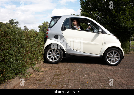 Ein sorgfältige Dame Fahrer über die Schulter schaut und sorgfältig kehrt ihr Daimler Chrysler Smart Auto in der Nähe einer Hecke in England Stockfoto