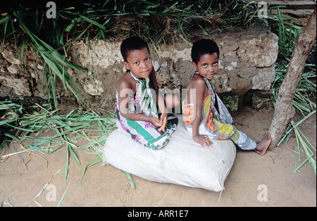 Afrika Kenia NACHWAHLEN junge kenianische Schwestern gekleidet in traditionellen Kanga Tuch sitzen auf Tasche von Futter für Heifer Projekt Kuh Stockfoto