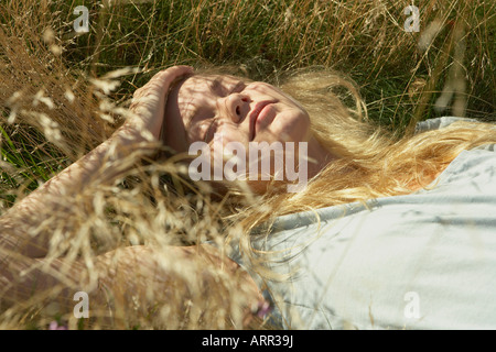 Junge Frau in langen Rasen liegen Stockfoto