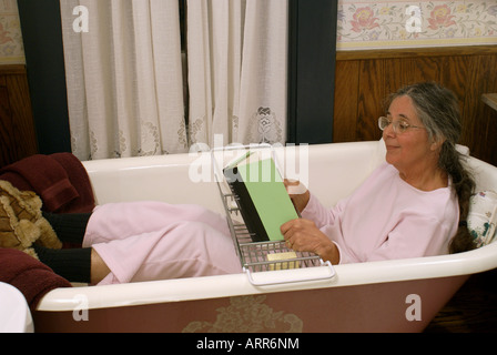 Frau Buch allein in leeren Badewanne Stockfoto