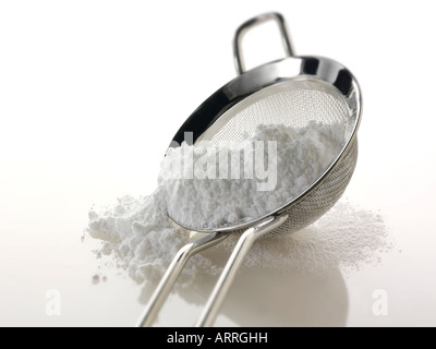 Puderzucker in ein Sieb vor einem weißen Hintergrund Stockfoto
