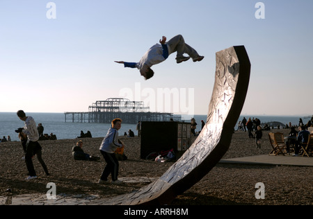 Ein Teenager führt einen Back Flip auf einem Strand von Brighton s Passacaglia Skulptur von Charles Hadcock Stockfoto