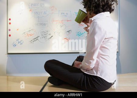 Frau sitzt am Schreibtisch, Kaffee trinken Stockfoto