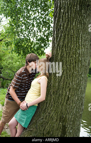 Teenager-Paar küssen in der Nähe von Baum Stockfoto