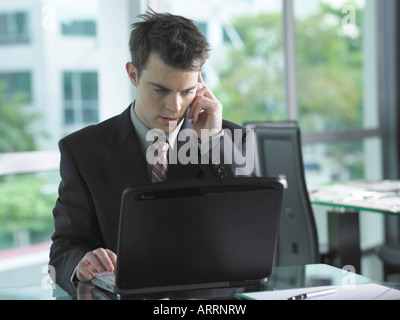 Geschäftsmann mit Laptop während des Gesprächs auf dem Handy Stockfoto