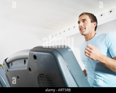 Mann trägt Kopfhörer auf Laufband im Fitnessstudio Stockfoto