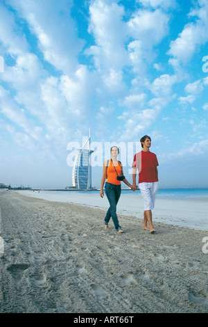 Westliche Touristen zu Fuß am Strand in der Nähe von Burj Al Arab Hotel in Dubai, Vereinigte Arabische Emirate Stockfoto