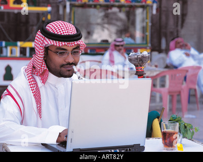 Saudi Mann arbeiten am Laptop und Rauchen Shisha in alte Stadt von Jeddah, Saudi-Arabien Stockfoto