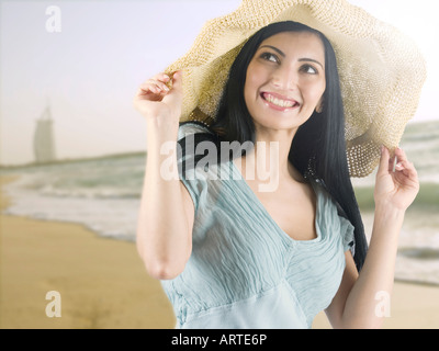 Frau trägt einen Sonnenhut mit am Strand in Dubai (Burj Al Arab Hotel im Hintergrund) Stockfoto