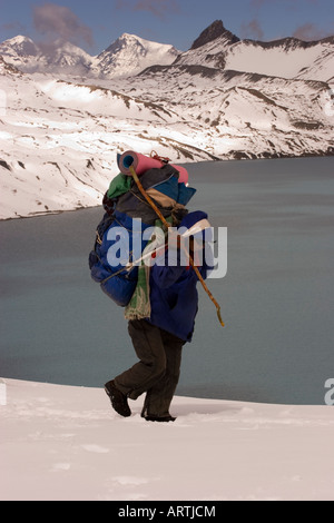 Porter tragen einer Last durch den Schnee Tilicho Lake in der Annapurna Region Nepal trekking. Stockfoto