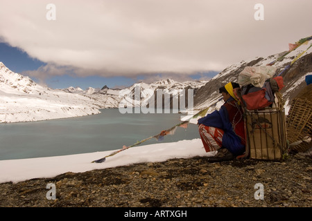 Porter Rest mit seiner Ladung am Tilicho Lake in der Annapurna Region Nepal trekking. Stockfoto