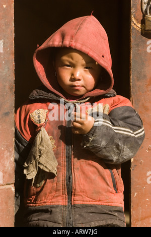 Lokalmatador stehend in einem Hauseingang entlang des Weges über Manang auf dem Annapurna Circuit Trek, Nepal. Stockfoto