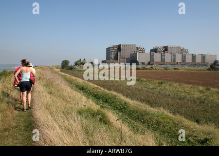 Menschen gehen für einen Spaziergang entlang der Mündung neben Bradwell Nuclear Power Station, Essex. Stockfoto