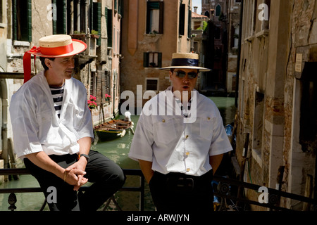 Zwei Gondolieri warten auf eine Brücke über einen der Kanäle in Venedig Italien. Stockfoto