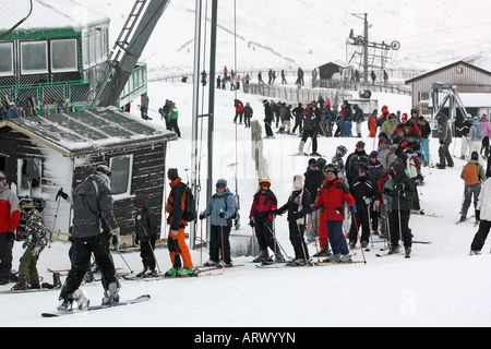 Skifahrer und Snowboarder warten, um auf dem Sessellift in Glenshee Ski-Zentrum in der Nähe von Braemar, Aberdeenshire, Schottland, Vereinigtes Königreich Stockfoto