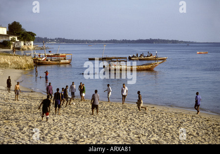 Eine Gruppe junger Männer spielen Fußball oder Fußball auf einem Sandstrand in der Nähe der steinernen Stadt Sansibar Tansania Ostafrika Stockfoto