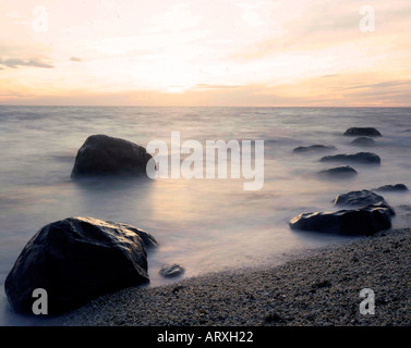 Blick auf große Felsen im Wasser in der Dämmerung auf den Long Island Sound in Greenport NY Stockfoto