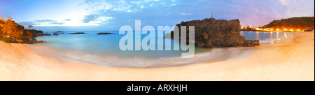 Super Weitwinkel-Ansicht der Waimea Bay in der Nacht. Langzeitbelichtung Schuss von Straßenlaternen und Mond beleuchtet. Springen Felsen auf der rechten Seite. Stockfoto