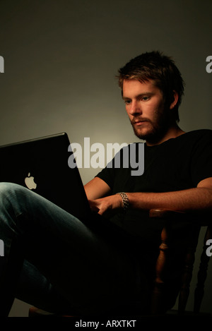 Modisch junger Mann in Jeans mit computer Stockfoto