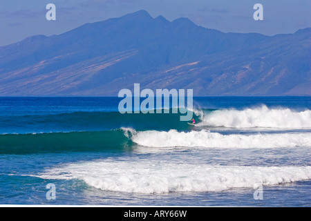 Eine einsame Surfer reitet eine saubere Welle in Honolua Bay, Maui, mit der Insel Molokai im Hintergrund. Stockfoto