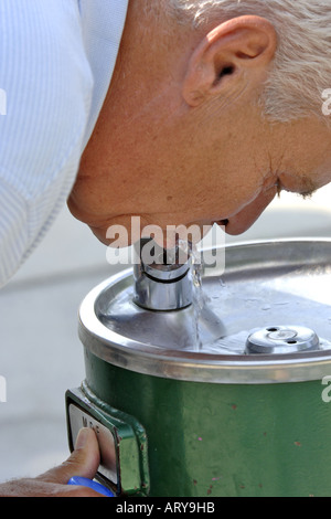 Nahaufnahme eines Senior männlichen nippen Wasser aus einem Brunnen. Stockfoto