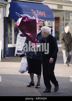 Zwei Damen teilen einen Witz auf der Straße über einen Blumenstrauß. Stockfoto