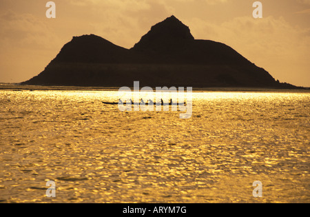 Gruppe paddeln Auslegerkanus im offenen Ozean bei Sonnenaufgang in Lanikai, Windward Oahu mit Moku Lua Insel im Heck Stockfoto