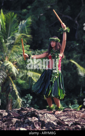 Junge Hula-Tänzerin in Ti Blatt Rock an hawaiischen Heiau (Tempel Website) mit Puili (Bambus Stöcke Schlitz) tragen Maile Blatt Lei Stockfoto