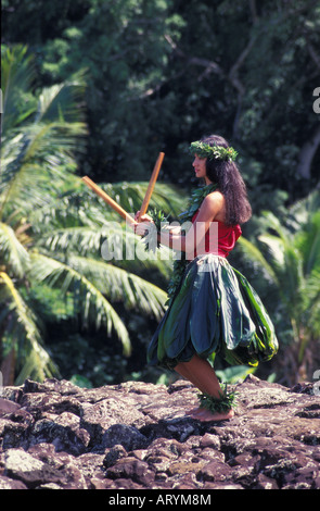 Junge Hula-Tänzerin in Ti Blatt Rock an hawaiischen Heiau (Tempel Website) mit Puili (Bambus Stöcke Schlitz) tragen Maile Blatt Lei Stockfoto