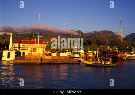 Lahaina Harbor mit einem Vollmond über den West Maui Bergen. Touristen, die nach dem Laden dock von einem Boot aus Gruppe Stockfoto