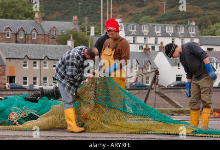 Fischer reparieren Fischernetze auf dem Pier im Hafen von Ullapool Stockfoto