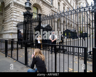 Mädchen spielen mit einer Handpuppe vor dem Tor der Downing Street, das von Polizisten 24 7 Westminster London UK bewacht wird Stockfoto