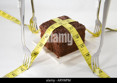 Schokoladenkuchen mit einem Maßband vermessen und Gabeln gedrückt gehalten. Stockfoto