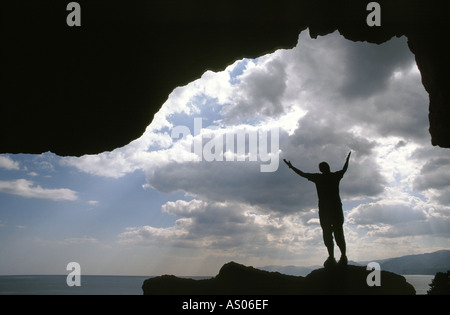 Eine Person steht in einer Höhle mit Wolken und Meer Stockfoto