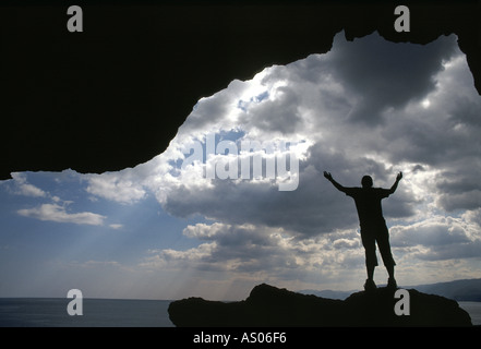 Eine Person steht in einer Höhle mit Wolken und Meer Stockfoto