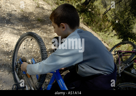Junge Halt, um seinem Mountain Bike Reifen, Vitrolles, Provence, Frankreich zu beheben. Stockfoto