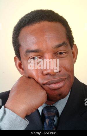 Ein schwarzer Geschäftsmann sucht ein bisschen müde, unglücklich oder nachdenklich ruht seinen Kopf auf seine Hand. Stockfoto