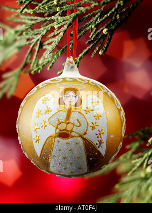 Traditionelle festlich geschmückte Weihnachtsengel-Kugel, die an Weihnachten hängt Baum mit Lichtern dahinter Stockfoto