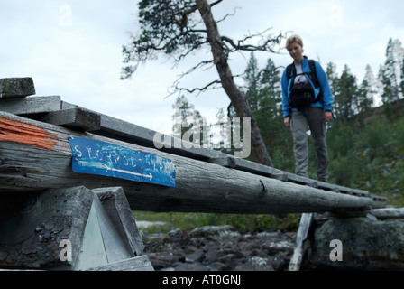 Wanderer, die über eine kleine Holzbrücke über einem Bach in den Rogen Nationalpark Harjedalen Schweden August 2007 Stockfoto