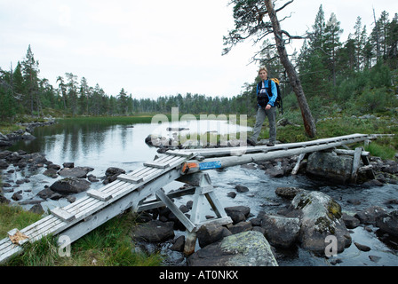 Wanderer, die über eine kleine Holzbrücke über einem Bach in den Rogen Nationalpark Harjedalen Schweden August 2007 Stockfoto