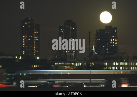 Ein voller Mond scheint über Gebäude und einem vorbeifahrenden Zug im Zentrum von London Stockfoto