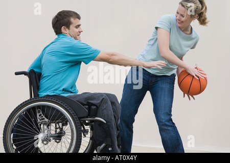 Seitenansicht eines jungen behinderten Mannes Basketball spielen mit einem Mitte Erwachsene Frau Stockfoto