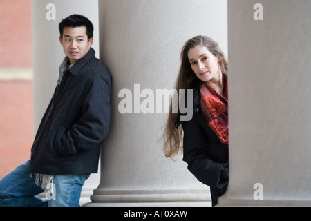Porträt einer jungen Frau, die hinter einer Säule und ein junger Mann sah sie spähen Stockfoto