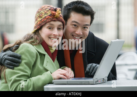 Porträt eines jungen Paares mit einem Laptop in einem Straßencafé Stockfoto