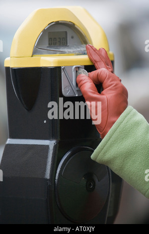 Nahaufnahme der Hand einer Person, die eine Münze in eine Parkuhr einfügen Stockfoto