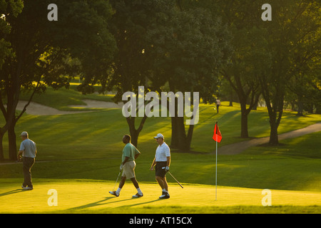 ILLINOIS Aurora drei Männer gehen auf Grün in der Nähe von Flagge Golfer auf Phillips Park Golf course Stockfoto