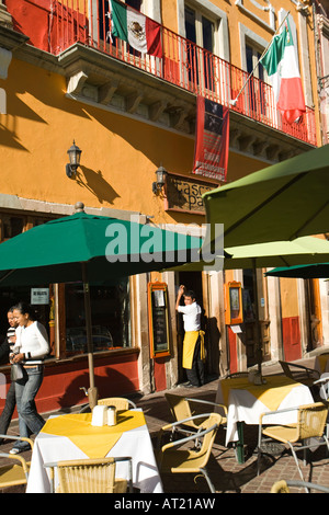 Mexiko Guanajuato Restauranttische in Plaza De La Paz jungen männlichen Kellner beobachten zwei Mädchen, die zu Fuß auf Bürgersteig Stockfoto