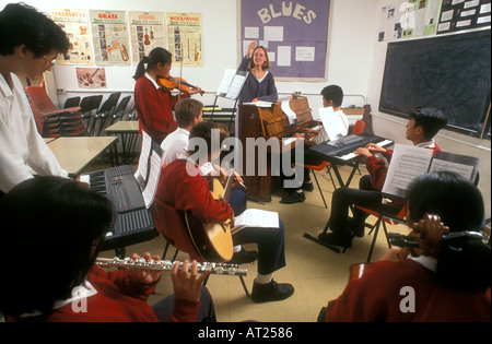 Musik KLASSE BAND GRUPPE LEHRER multikulturelle Band Musik Schüler & Lehrer Sie dirigieren, spielen verschiedene Instrumente in der Schule Musik Class Zimmer Stockfoto