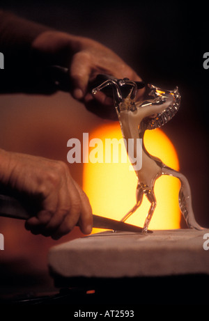 MURANO KUNSTGLASHÜTLER GLASBLÄSERIN Formt in einer renommierten Murano-Glasfabrik Venedig Italien ein stachelhaftes Glaspferd aus einem Ofen im Hintergrund Stockfoto